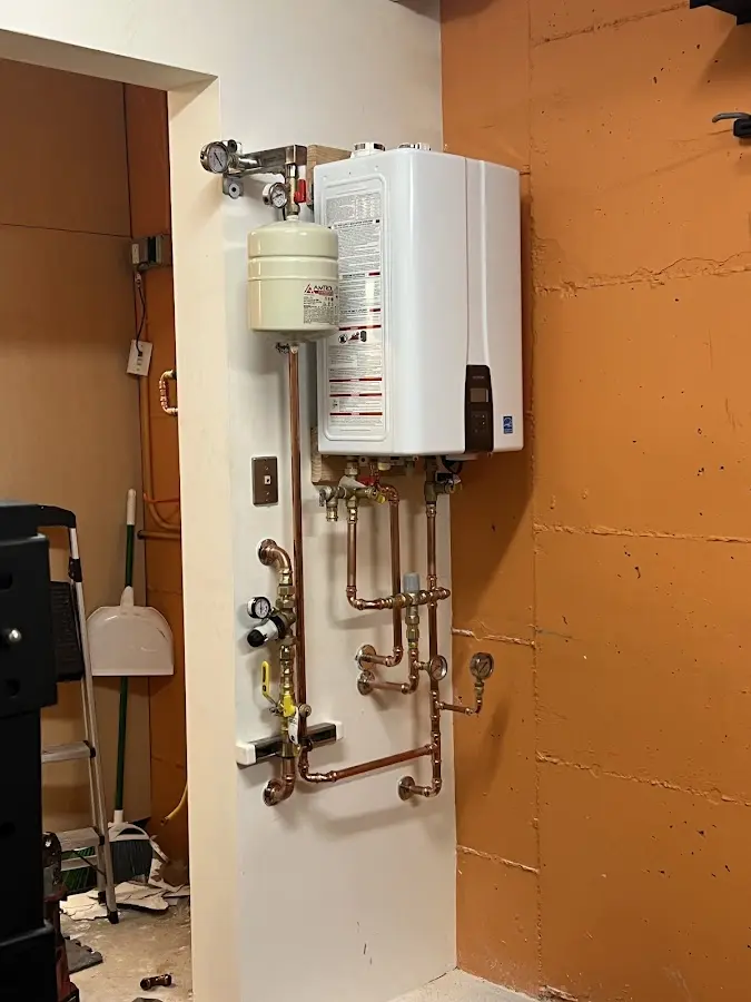 Plumbing technician inspecting water heater connections in Reynolds